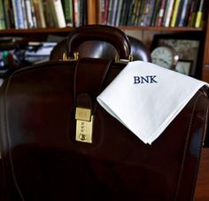 a brown briefcase with a white napkin on it sitting in front of a bookshelf