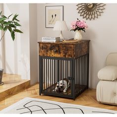 a dog in a cage sitting on the floor next to a table with flowers and books