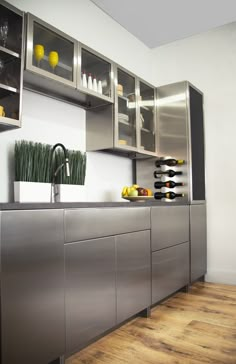 a kitchen with stainless steel cabinets and wine bottles on the counter top, along with wooden flooring