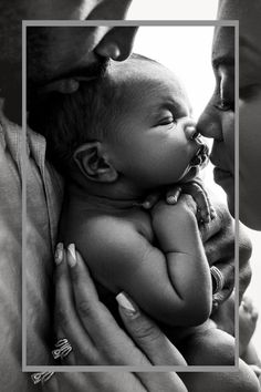 a woman holding a baby in her arms and kissing the man's face with his eyes closed