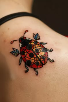 a lady bug tattoo on the back of a woman's shoulder