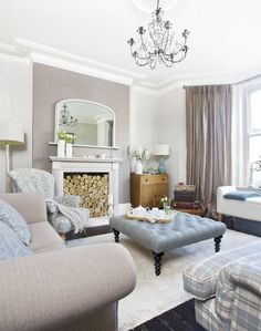 a living room filled with furniture and a fire place under a chandelier in front of a window