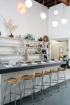 an empty bar with stools and bottles on the shelves