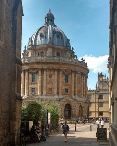 people are walking around in front of an old building with a dome on the top