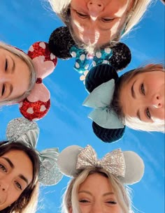 four girls wearing minnie mouse ears looking up at the camera