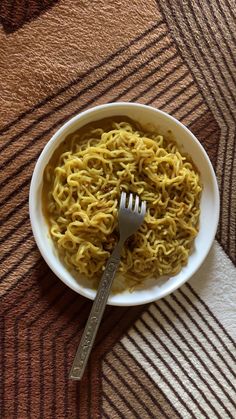 a white bowl filled with noodles on top of a brown and black striped table cloth