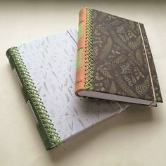 two notebooks sitting next to each other on top of a white table with green trim