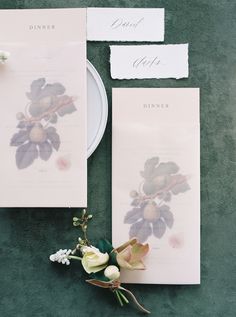 the table is set up with flowers and menus on top of each other, along with an empty plate