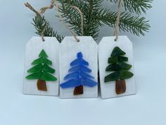 three ceramic christmas tree ornaments hanging from twine