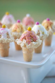 small ice cream cones with sprinkles and toppings in them on a tray