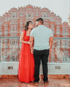 a man and woman standing next to each other on top of a building