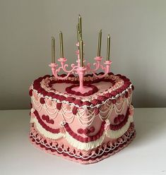 a pink and red cake with candles on top