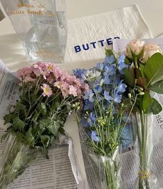 three vases filled with flowers sitting on top of a newspaper