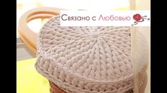 a knitted basket sitting on top of a wooden table next to a white sign