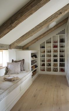 an attic bedroom with white walls and wooden flooring, built in shelving units