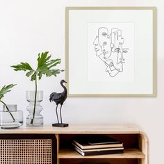 a black bird sitting on top of a wooden shelf next to a vase filled with plants