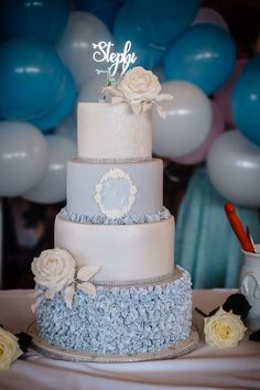 a three tiered cake sitting on top of a table next to blue and white balloons