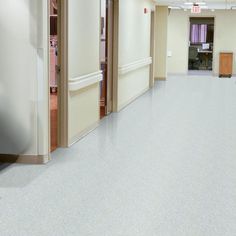 an empty hospital hallway with white floors and doors