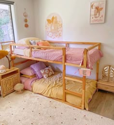 there is a bunk bed in the room with pink and yellow pillows on the floor