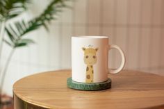 a giraffe mug sitting on top of a wooden table next to a potted plant