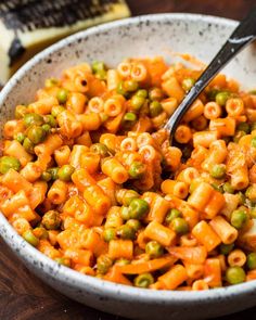 a white bowl filled with pasta and peas