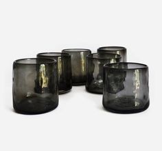 six black glass tumblers sitting next to each other