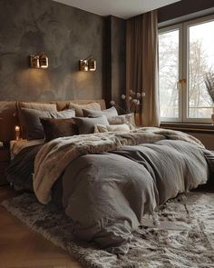 a large bed sitting in a bedroom next to a window with candles on the side