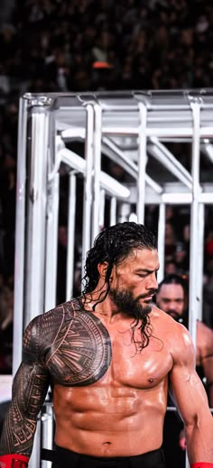 a man with long hair and tattoos on his arm standing in front of a crowd