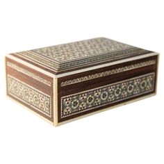 a wooden box with an intricate design on the lid and sides, sitting against a white background