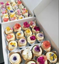 there are many cupcakes in the box and one is decorated with flowers on it