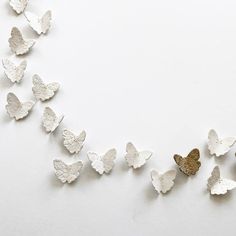 several white and gold butterflies are arranged in a row on a white background with space for text