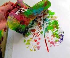 someone is painting leaves with watercolors on paper