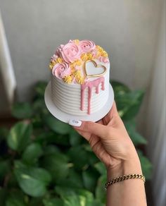 a person holding a cake with flowers on it