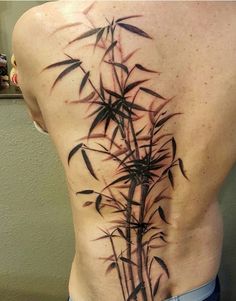 the back of a man's body with black ink on it and bamboo leaves