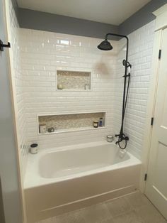 a bathroom with white tile and black fixtures on the shower head, tub, and shelves