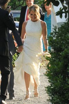 the bride and groom are holding hands as they walk down the path with their guests