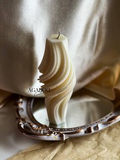 a white candle sitting on top of a table next to a mirror with a chain around it