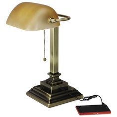 an old fashioned desk lamp with a charger on the side and a phone plugged into it