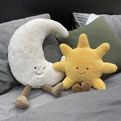 two stuffed animals laying on top of a bed next to each other, one has a crescent and the other is a star