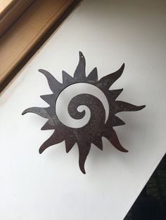 a metal sun decoration on the side of a wall next to a wooden window sill