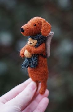 a hand holding a tiny teddy bear in it's arms