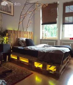 a bed made out of wooden pallets with lights on the bottom and headboard