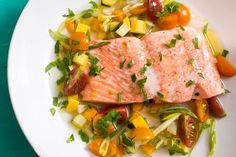 a white plate topped with salmon and veggies on top of a green table