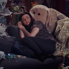 a woman laying on top of a couch next to stuffed animals