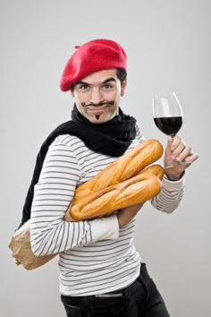 a man with a mustache holding bread and a glass of red wine in his hand