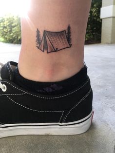 a woman's foot with a small camping tent tattoo on her left side ankle