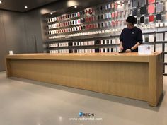 a man standing at a counter in front of a wall full of shelves filled with cell phones