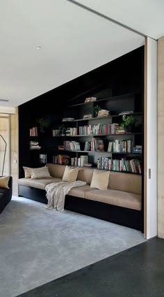 a living room with couches and bookshelves next to a sliding glass door