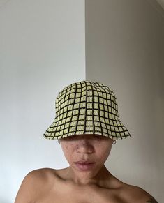 a shirtless man wearing a yellow and black plaid bucketer hat over his head