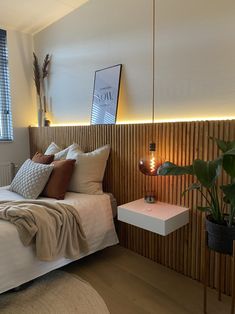 a bed sitting next to a window with a plant on it's headboard